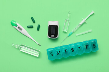 Wall Mural - Composition with pulse oximeter, syringe, thermometer and medicines on green background