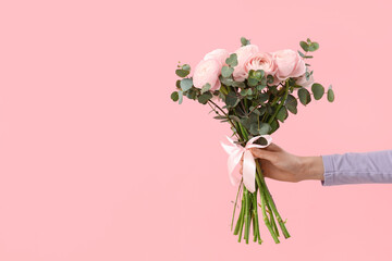 Wall Mural - Female hands with bouquet of ranunculus flowers and eucalyptus on pink background