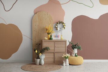 Wall Mural - Chest of drawers with vases, flowers and Easter wreath on color wall in room