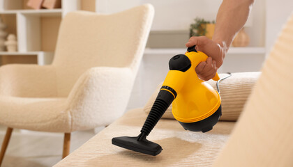 Wall Mural - Man cleaning sofa with steam cleaner at home, closeup