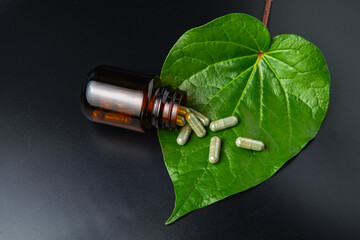 Wall Mural - Herbal capsules Betel pepper leaf, pills Wildbetal leafbush, green leaf on a black background