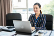 © Fahng - Happy mature business woman entrepreneur in office using laptop at work, smiling professional middle aged 40 years old female company executive wearing suit working on computer at workplace