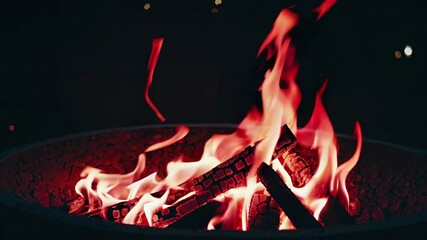 Poster - Cozy campfire with glowing orange and red flames in a dark setting, creating warmth and ambiance. Outdoor relaxation and adventure concept