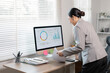© David - Young business finance market analyst in standing working at office  .Business woman analyze document Graphs and diagramm on Desktop Computer screen.