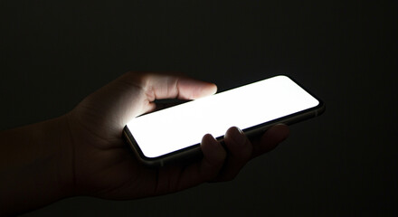 Poster - Smartphone in hand with bright light from screen. Smartphone with bright screen in hand in the dark