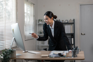 Wall Mural - attractive business asian woman working of reading Documents accounting file financial report, tax invoice on her documents project with laptop computer in the workplace office.
