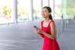© StockPhotoRepublic - Young Asian Woman in Red Dress Using Phone Outdoors a Modern Office Building