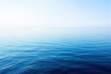 Poster - Serene ocean view with calm blue water stretching into a soft, hazy horizon under a clear sky.