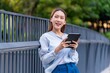 © StockPhotoRepublic - Asian Businesswoman Using Tablet In Front of A Modern Office Building In the Financial District