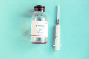 Coronavirus vaccine bottle and syringe on blue pastel background. Minimal concept