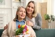 © New Africa - Family portrait of smiling woman with bouquet of tulips and her daughter at home. Happy Mother's Day
