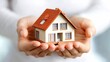 © Arc std. - Hands gently holding a small house model.