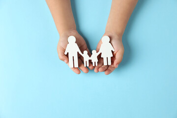 Wall Mural - Child holding figure of family on light blue background, top view