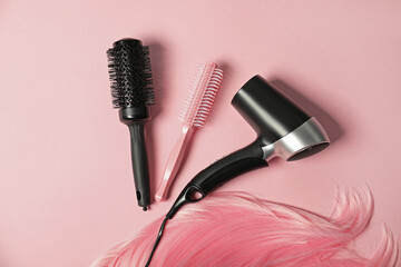 Wall Mural - Stylish round brushes, hairdryer and lock of dyed hair on pink background, flat lay