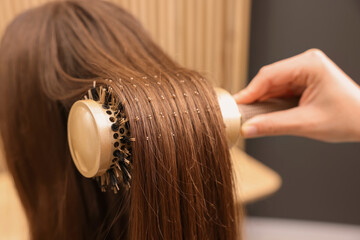 Wall Mural - Hairdresser styling client's hair with round brush in salon, closeup