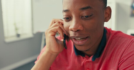 Wall Mural - An experienced sales department company employee sits at desk in office, laptop stands in front of him, adark-skinned man is talking on phone, making an order, doing business, arranging meetings