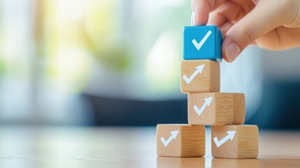 Poster - A hand places a blue checkmark block on a stack of wooden blocks, symbolizing accomplishment, progress, and organization.