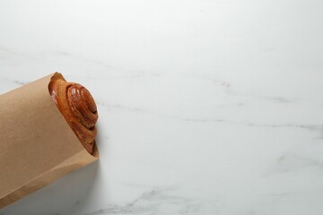 Sticker - Paper bag with freshly baked bun on white marble table, top view. Space for text