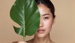 © Janis - Serene woman with tropical leaf on neutral background, nature beauty concept