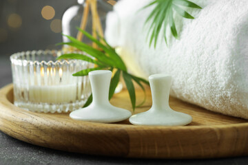 Wall Mural - Spa stones, burning candle, towel and green leaves on grey table, closeup