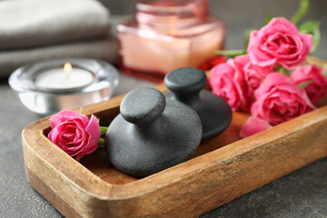 Wall Mural - Spa stones, rose flowers and candles on grey table, closeup