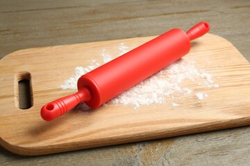 Wall Mural - Red rolling pin and board with flour on wooden table, closeup