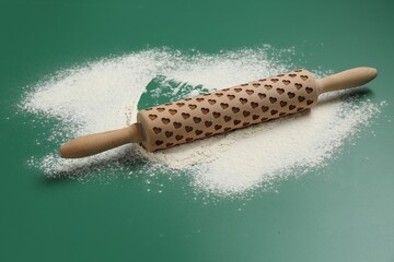 Wall Mural - Wooden rolling pin and flour on green background