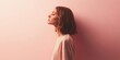 © Diffin - A serene woman in arafed attire stands with closed eyes, embodying tranquility against a soft pink wall backdrop.