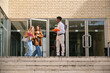 © Ladanifer - Group of diverse university students chatting together while walking out of campus building