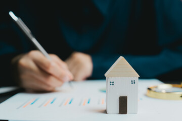Poster - Small Wooden House Model on Table with Hand Writing in Background