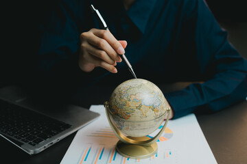 Poster - Business Professional Pointing to Globe on Desk with Laptop and Charts