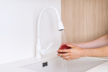 Wall Mural - Modern kitchen sink with faucet washing apple in bright home environment