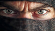 © jaya - Close-up portrait of a man's intense eyes peering from beneath a dark cloth covering his face, set against a blurred, shadowy background, suitable for themes of mystery, suspense, or danger