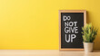 © Bonsales - Bright yellow message board encouraging perseverance with the phrase DO NOT GIVE UP prominently displayed against a cheerful backdrop