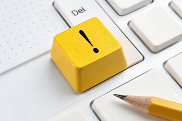 Poster - Attention Required: A close-up shot highlights a striking yellow exclamation point key on a keyboard, along with a pencil, conveying the need for awareness and focus. 