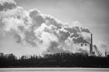 A black and white photo of a factory with smoke billowing out of it