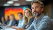 © Eg - Confident businessman at meeting, colleagues blurred background, corporate strategy