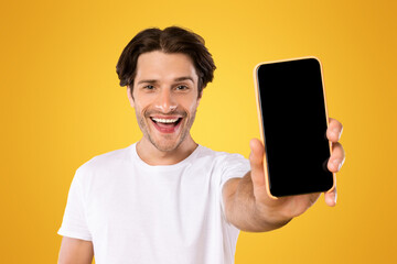 Poster - Mobile Application Ad. Portrait Of Excited Man Showing Smart Phone Black Empty Screen Recommending App Standing Over Yellow Orange Studio Background. Cellphone Display Mock Up, Check This Website