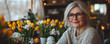 © VeloonaP - international woman celebration concept.senior woman with glasses smiles warmly festive Easter table adorned with yellow tulips and decorative