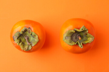 Wall Mural - Delicious fresh juicy persimmons on orange table, flat lay