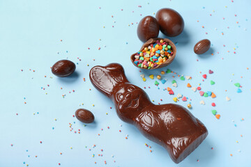 Wall Mural - Chocolate Easter bunny with eggs and sprinkles on blue background