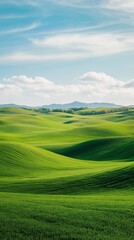 Poster - Lush green fields create a mesmerizing pattern of rolling hills leading to mountains under a sky filled with fluffy clouds, forming a tranquil and picturesque landscape