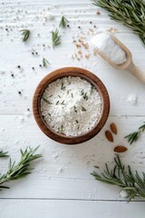 Wall Mural - Rosemary herb sea salt in wooden bowl with almonds and peppercorns on white table