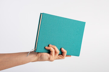 Wall Mural - Blank blue book cover in hand on white background.