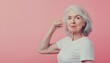 © Habibah - Strong senior woman flexing her arm against pink background