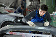© JackF - Car bumper repair in car service - professional car painter polishes and prepares the bumper before painting