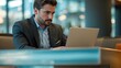 © VistaVisions - Business professional executive working on laptop in office lobby couch, surfing searching internet
