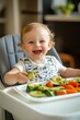© fahmy - A happy toddler eats small bites of avocado and soft-cooked veggies. The high chair tray is neatly arranged with healthy