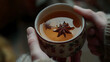 © Issara - of hands holding a warm cup of tea with cinnamon and star anise
