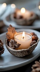 Warm candle in autumn-themed bowl with leaves and pinecones decor